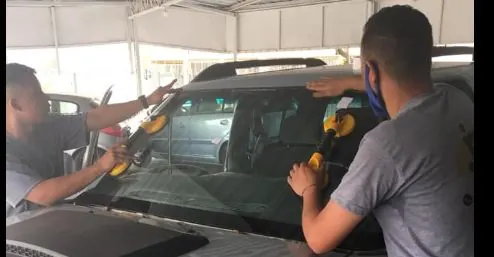 Dois profissionais da JR Auto Vidros instalando um para-brisa com ventosas