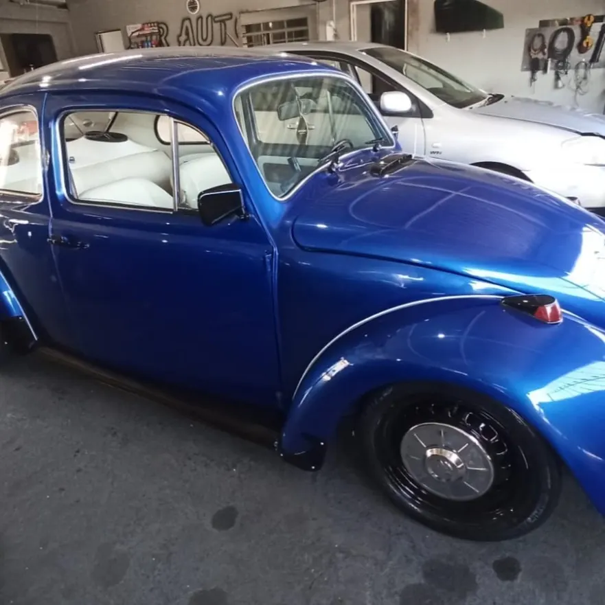 Fusca azul estacionado dentro da oficina da JR Auto Vidros